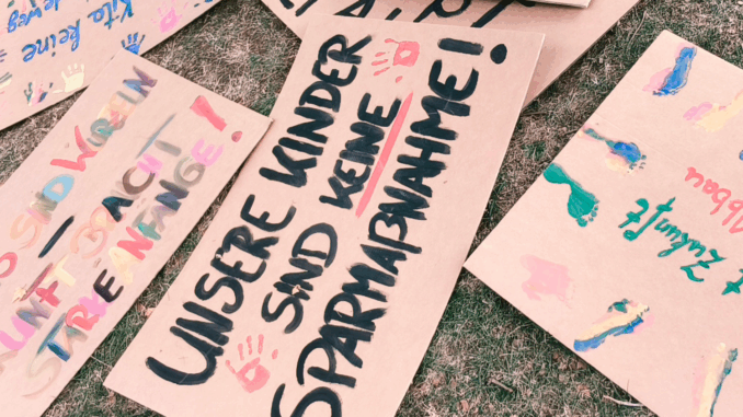 Protestplakate einer Leipziger Demonstration gegen Kürzungen im Kita-Bereich – mit der Botschaft: „Unsere Kinder sind keine Sparmaßnahme“.